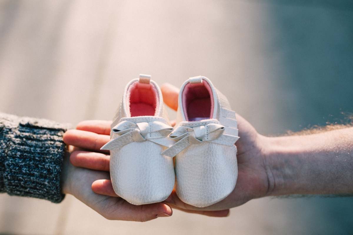 Hands holding a pair of baby shoes